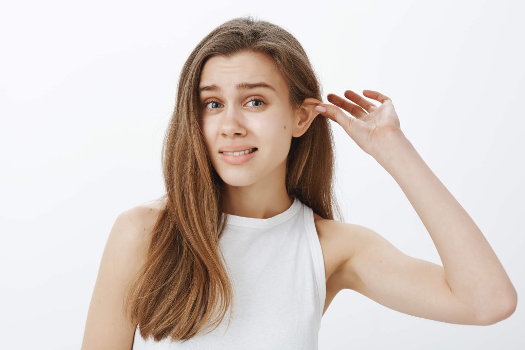 kadın hasta elleriyle kepçe kulak gösteriyor.